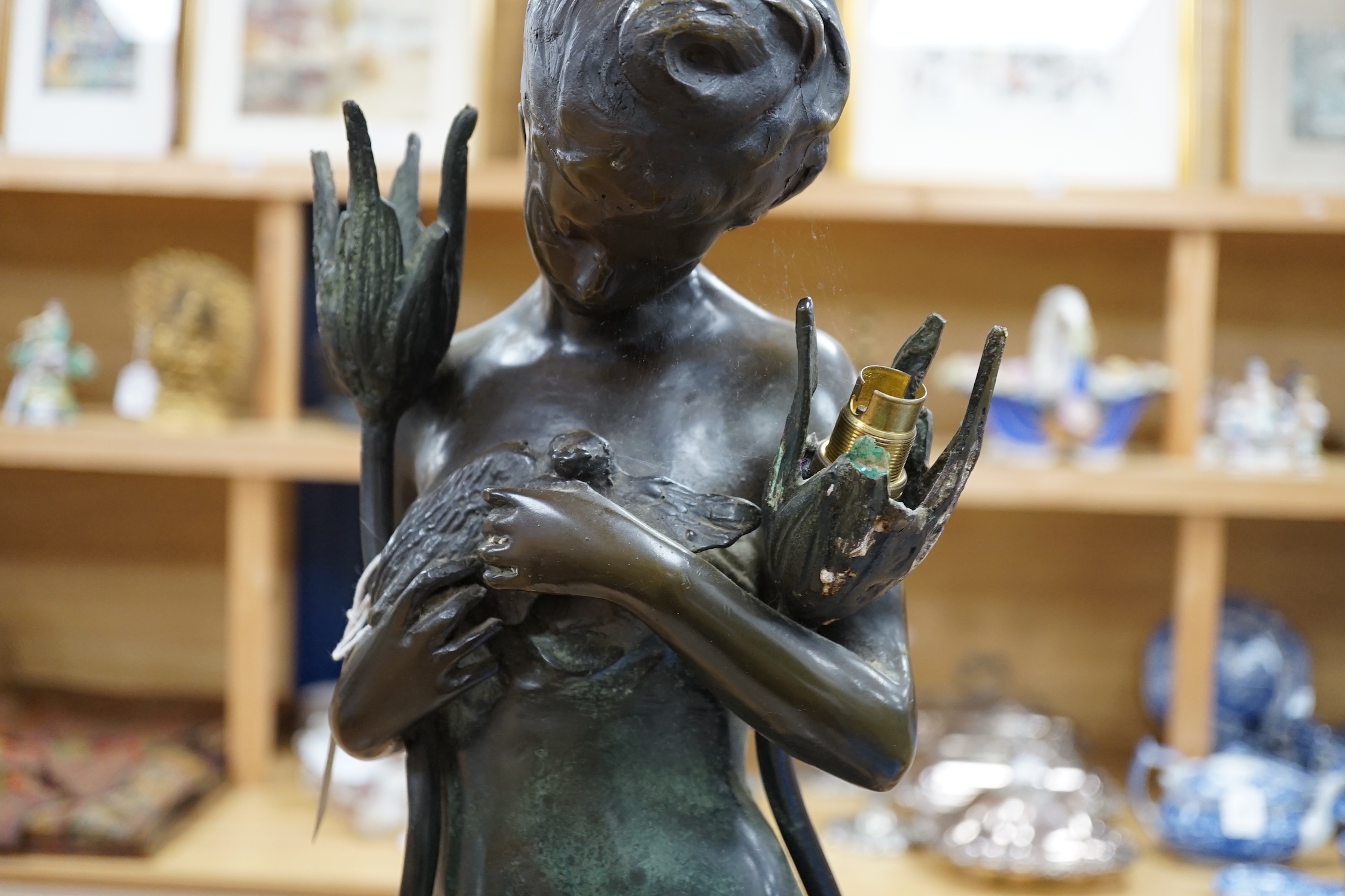 A figural bronze two branch floor standing lamp in the form of a lady holding a bird, indistinct signature, 76cm high